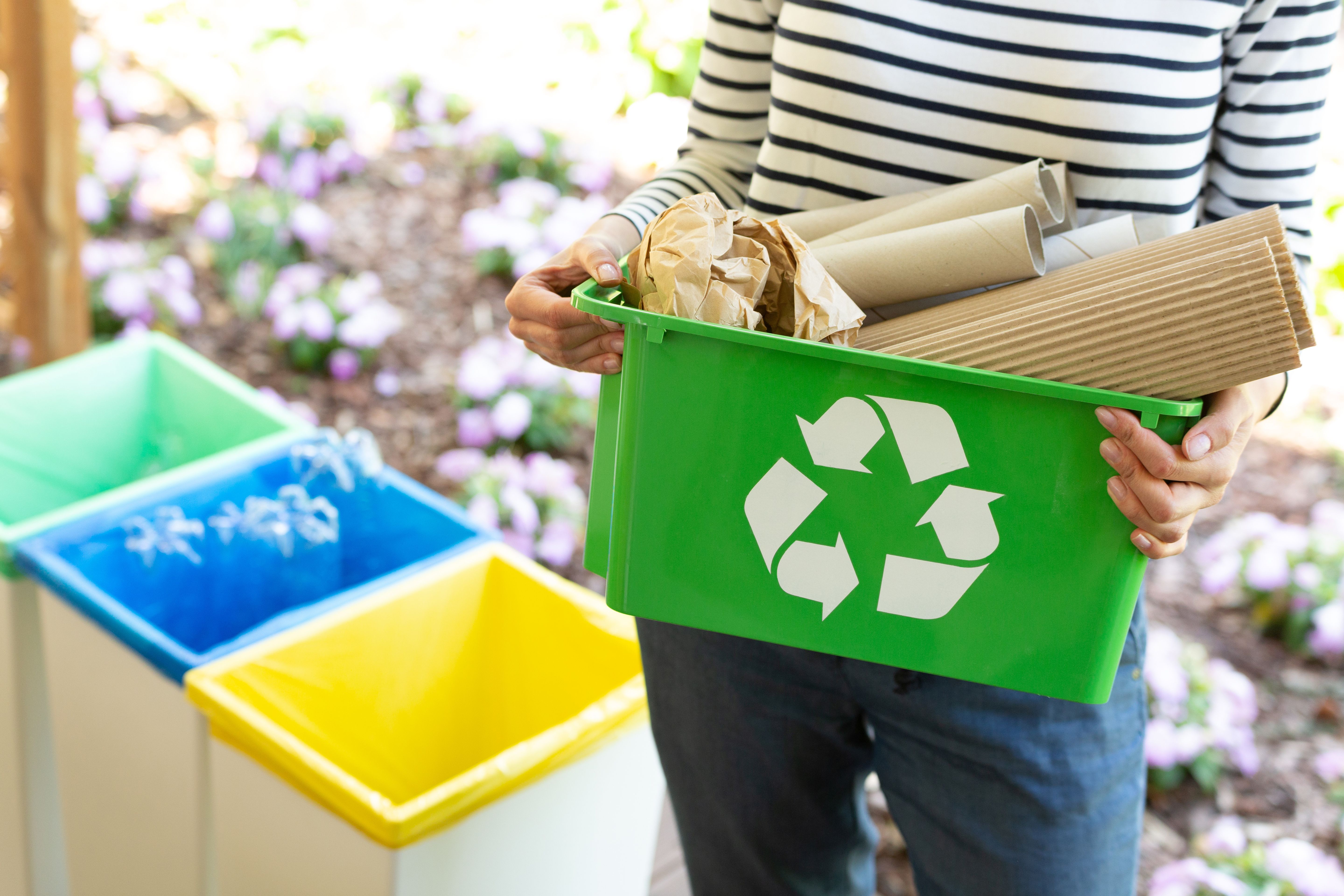 Close-up of a green basket with a recycling symbol with papers h Close-up of a green basket with a recycling symbol with papers h