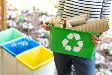 Close-up of a green basket with a recycling symbol with papers h Close-up of a green basket with a recycling symbol with papers h