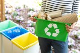 Close-up of a green basket with a recycling symbol with papers h