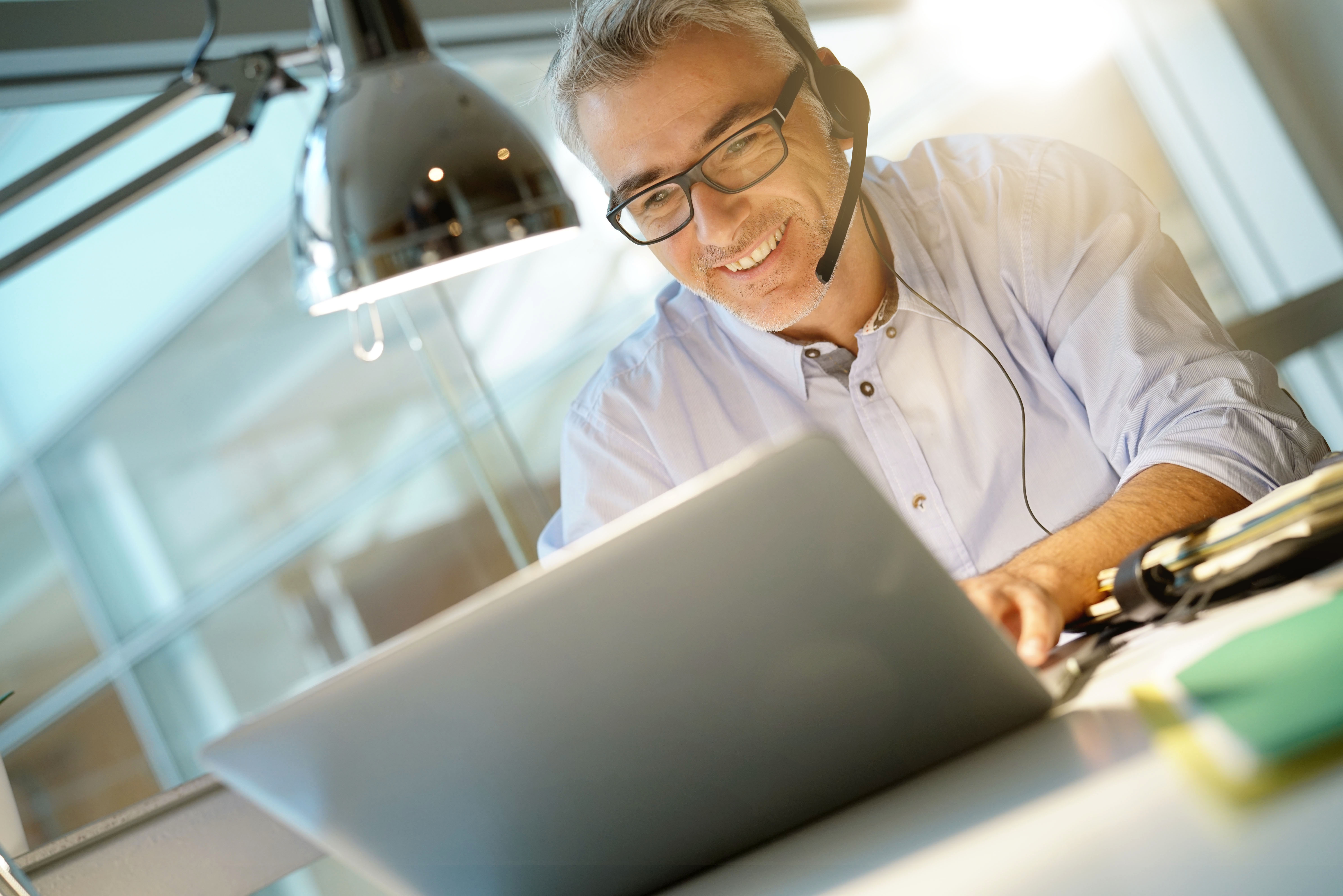 Office worker with headset on while having video conference Office worker with headset on while having video conference