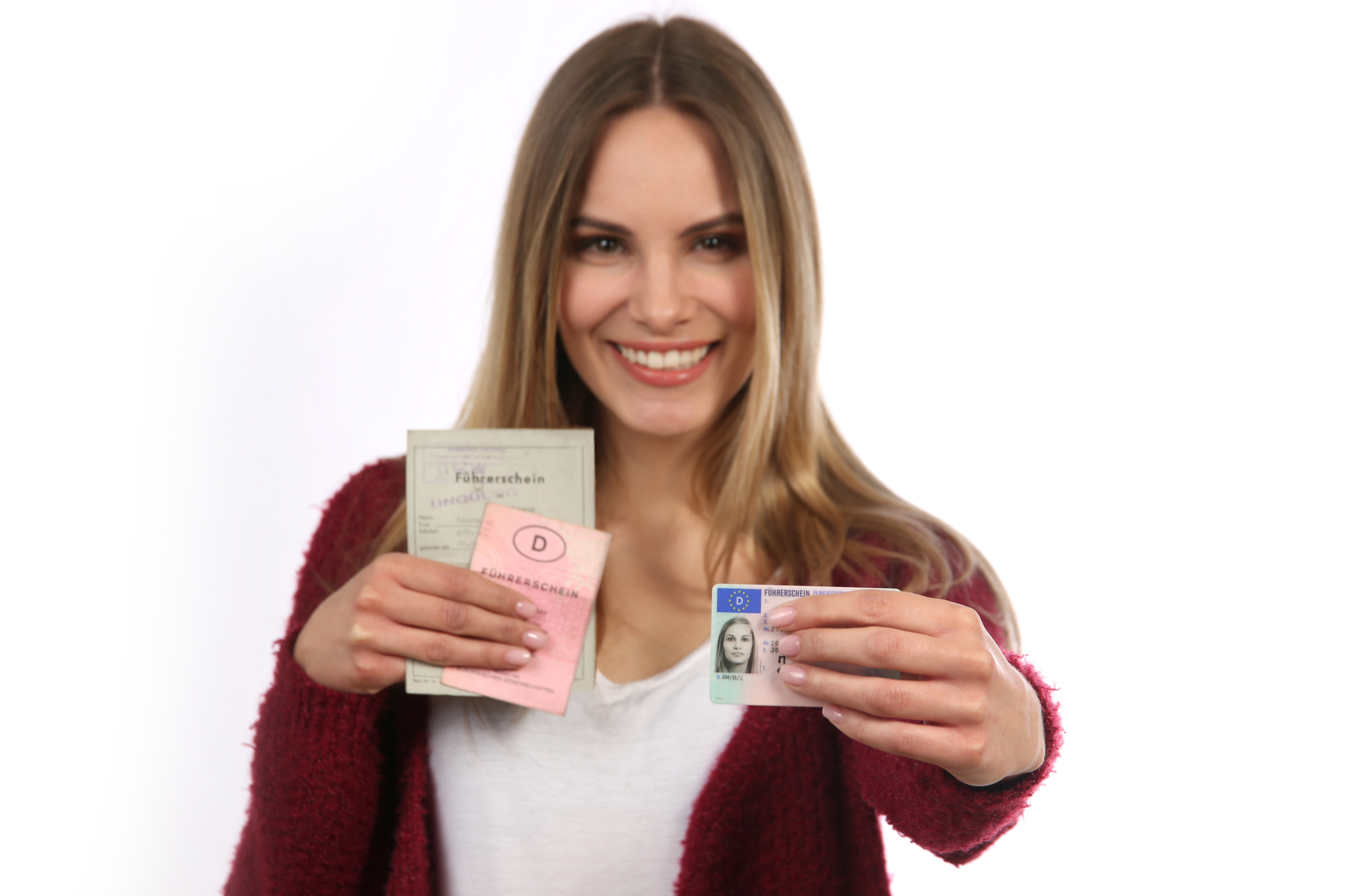 Junge Frau zeigt lächelnd alte und neue deutsche Führerscheine