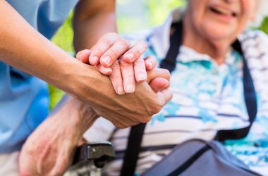 Nurse consoling senior woman holding her hand